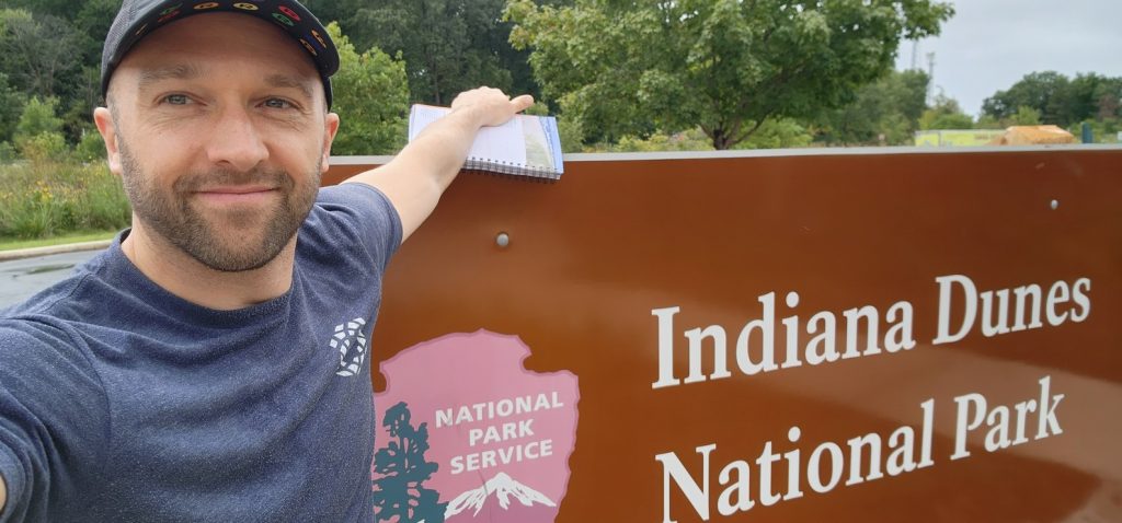 Photo of the author in front of the Indiana Dunes National Park sign.